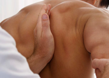 Mani del terapista durante un massaggio alla schiena